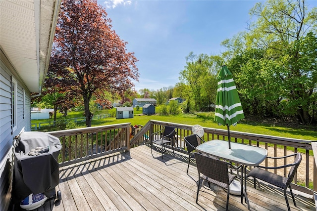 wooden terrace with outdoor dining area, a grill, and a lawn