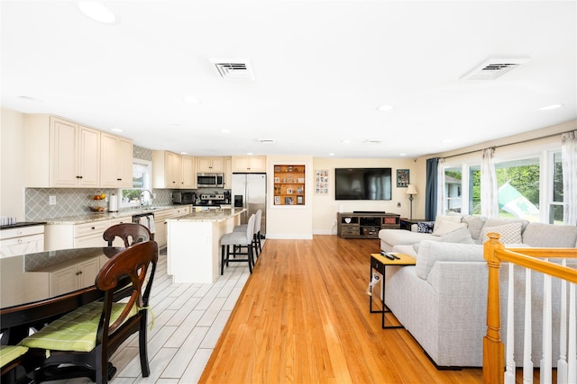 living room featuring light wood finished floors, visible vents, and recessed lighting