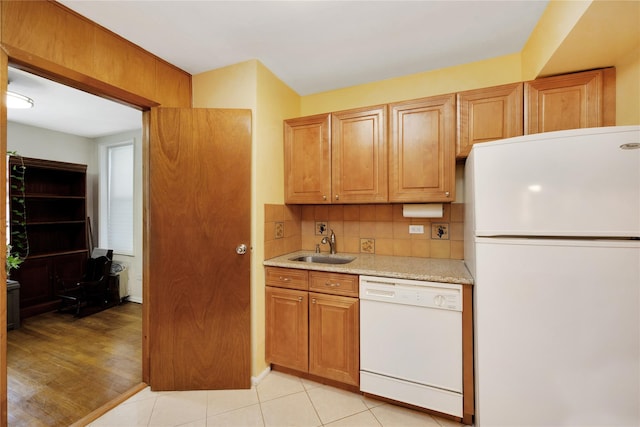 kitchen featuring brown cabinets, light countertops, a sink, white appliances, and tasteful backsplash