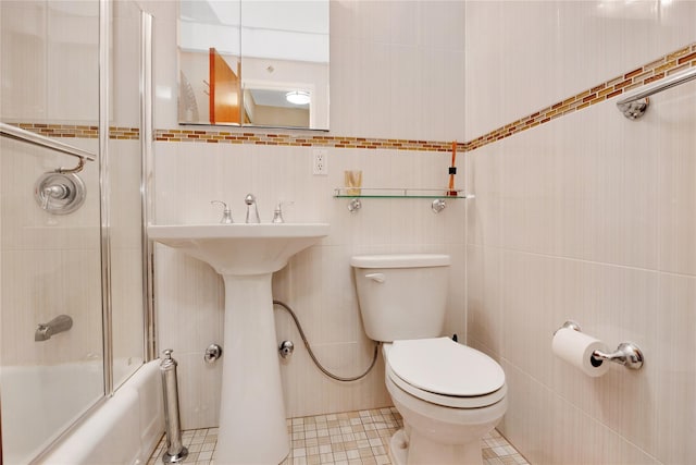 full bathroom with tile walls, combined bath / shower with glass door, tile patterned flooring, and toilet