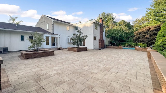 rear view of property featuring a chimney, central AC unit, and a patio area