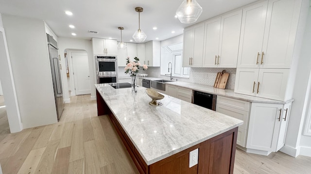 kitchen with tasteful backsplash, stainless steel double oven, light wood-style floors, dishwasher, and a sink
