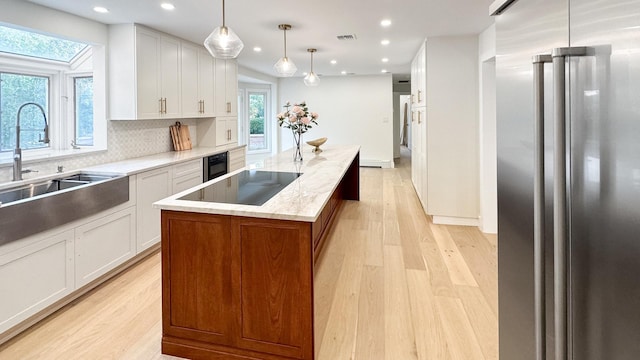 kitchen featuring a center island, light wood-type flooring, high end fridge, and a sink