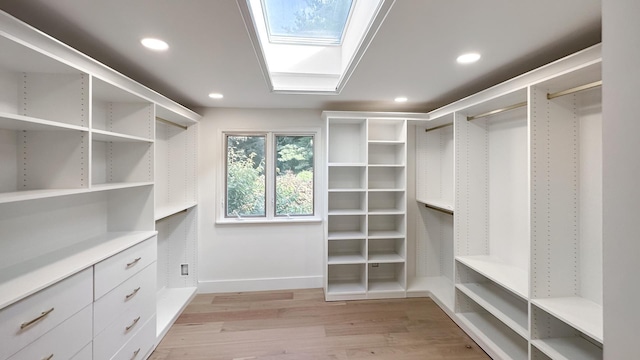 walk in closet featuring light wood-type flooring and a skylight