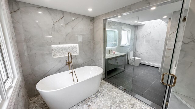 bathroom featuring a freestanding tub, toilet, vanity, and tile walls