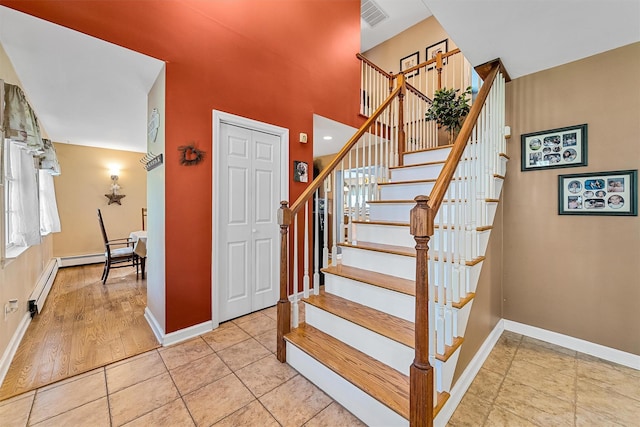 stairs with a baseboard radiator, visible vents, and baseboards