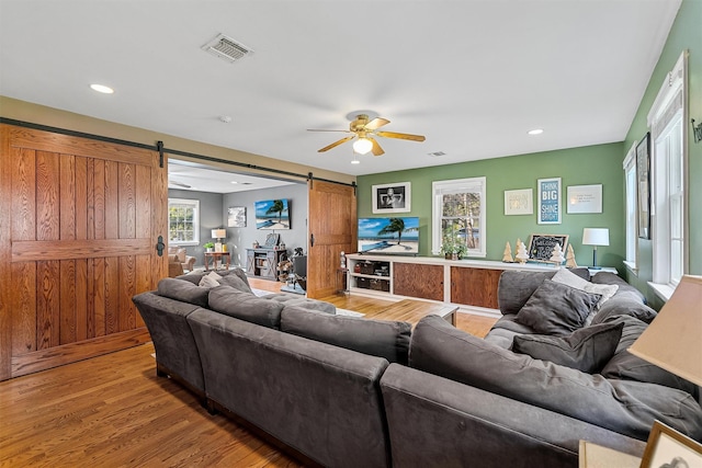 living area featuring recessed lighting, a barn door, light wood finished floors, visible vents, and a ceiling fan