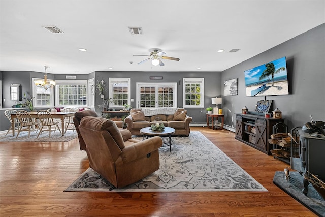 living area featuring wood finished floors, visible vents, and ceiling fan with notable chandelier