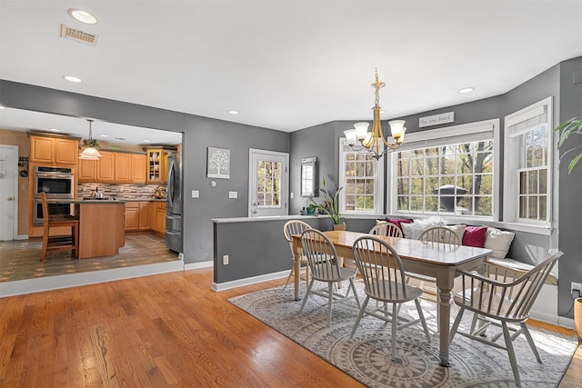 dining space featuring a notable chandelier, visible vents, light wood-style flooring, and plenty of natural light