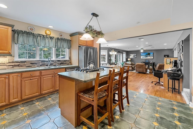 kitchen with recessed lighting, a sink, stainless steel appliances, a kitchen breakfast bar, and ceiling fan with notable chandelier