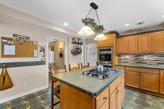 kitchen featuring decorative backsplash, appliances with stainless steel finishes, visible vents, dark countertops, and a kitchen bar