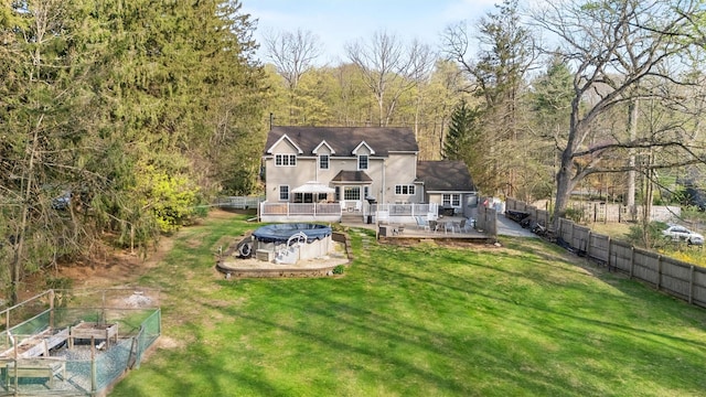 back of property with a lawn, a deck, a vegetable garden, and fence private yard