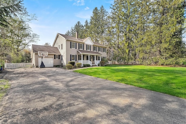 colonial-style house with a front lawn, a garage, covered porch, aphalt driveway, and fence