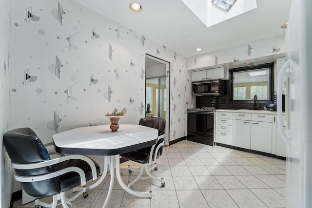103 S Nauraushaun Rd, Pearl River, NY 10965 - kitchen with black appliances, visible vents, white cabinetry, a skylight, and wallpapered walls