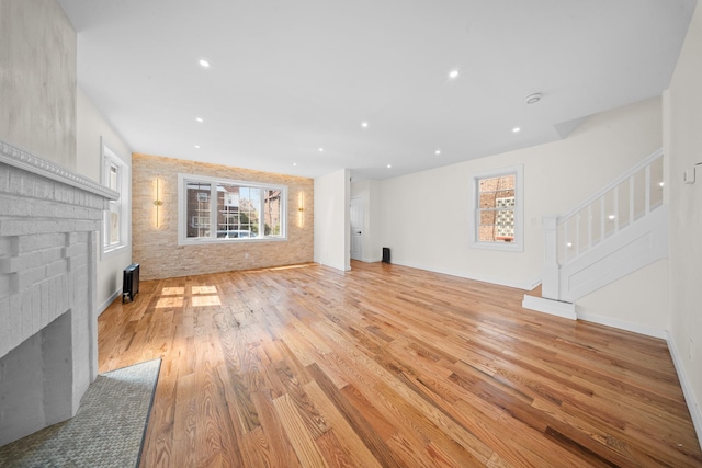 13107 229th St, Laurelton, NY 11413 - unfurnished living room with light wood finished floors, plenty of natural light, a fireplace, and stairway