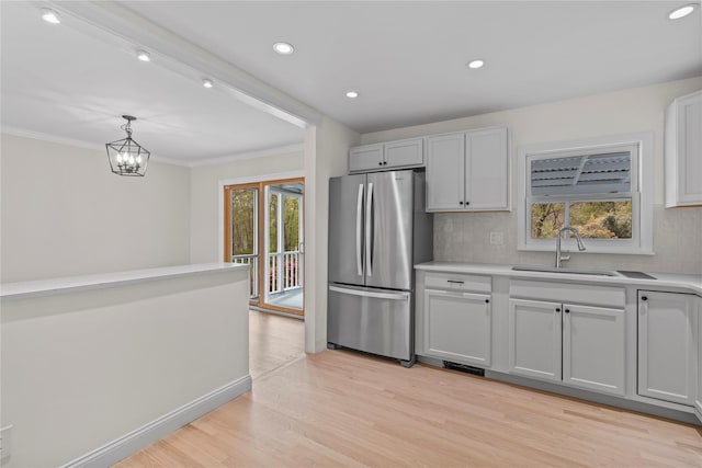 kitchen with light countertops, a sink, freestanding refrigerator, and tasteful backsplash