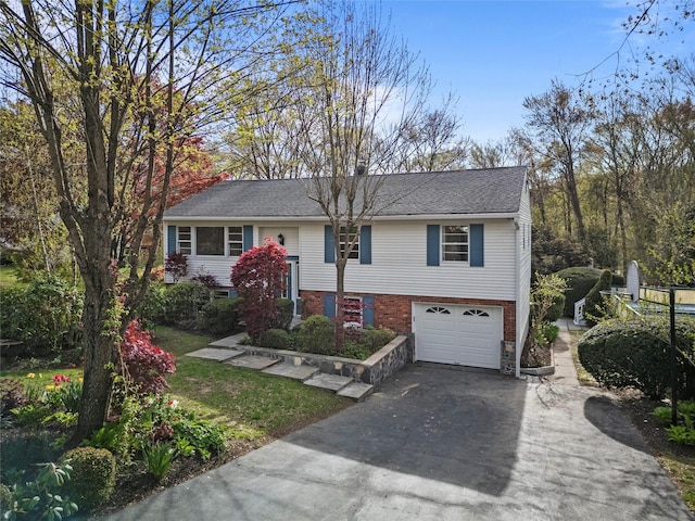 bi-level home with aphalt driveway, brick siding, and a garage