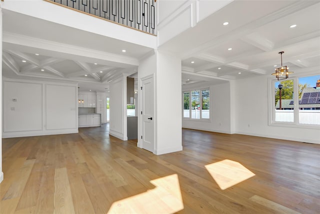 unfurnished living room with beamed ceiling, light wood-style flooring, a chandelier, and coffered ceiling
