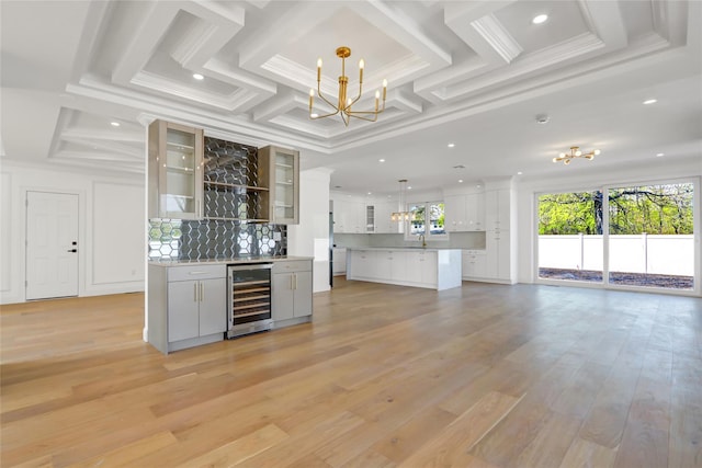 interior space featuring bar area, a sink, an inviting chandelier, crown molding, and beverage cooler