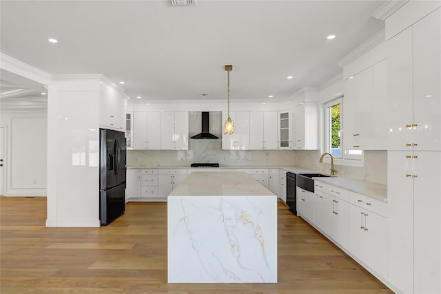 kitchen featuring wall chimney range hood, a sink, black appliances, white cabinets, and recessed lighting