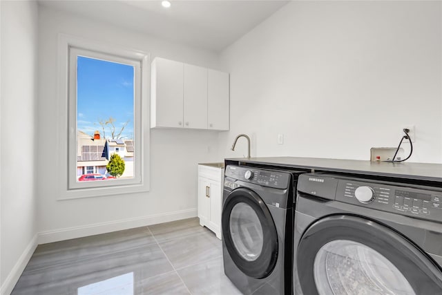 washroom with cabinet space, baseboards, washer and dryer, and a sink