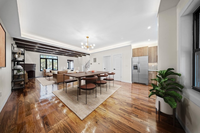22518 Mentone Ave, Laurelton, NY 11413 - dining space with a chandelier, light wood-style floors, a fireplace, and baseboards