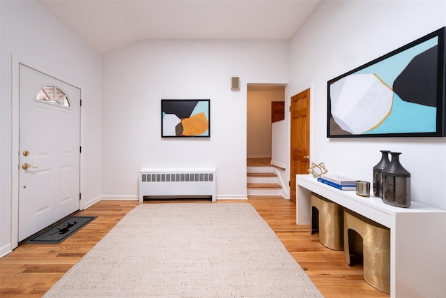 entryway with stairway, radiator, baseboards, light wood-type flooring, and lofted ceiling