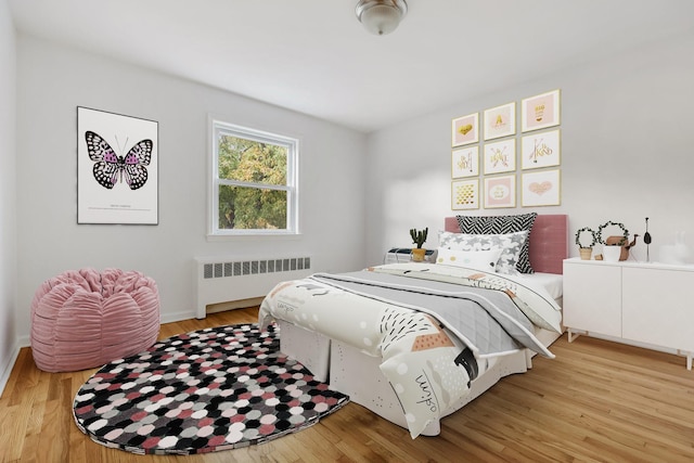 bedroom with baseboards, radiator, and wood finished floors