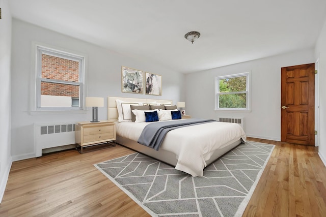 bedroom with baseboards, radiator, and light wood-style floors
