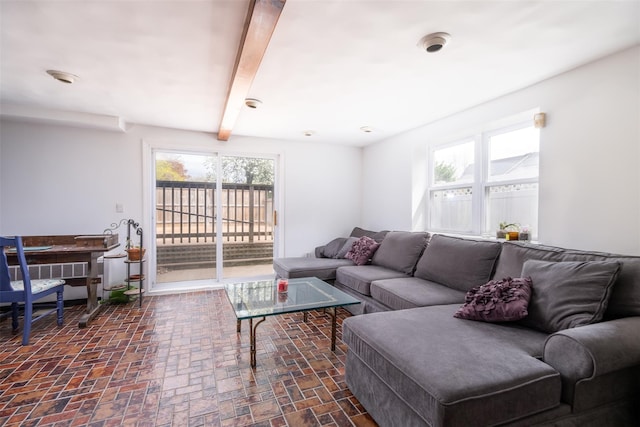 living room with a wealth of natural light, brick floor, and beam ceiling