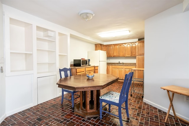 dining space featuring baseboards and brick floor
