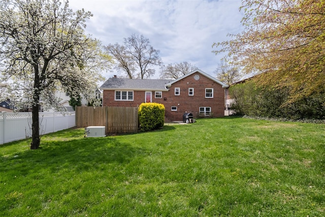 rear view of house with a chimney, brick siding, fence, and a lawn