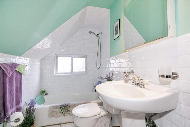 full bath featuring a sink, tiled shower / bath, toilet, and tile walls