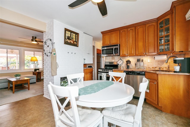kitchen with tasteful backsplash, a sink, stainless steel appliances, a ceiling fan, and brown cabinetry