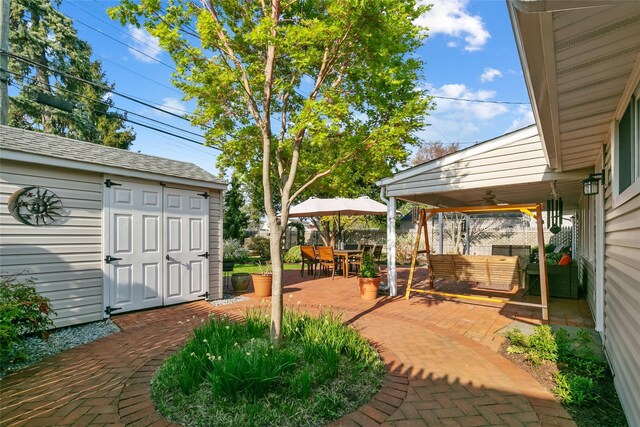 view of patio featuring outdoor dining area, an outdoor structure, a ceiling fan, an outdoor hangout area, and fence
