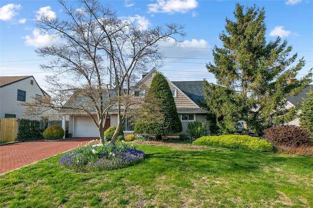view of front facade featuring a shingled roof, decorative driveway, fence, a front lawn, and a garage
