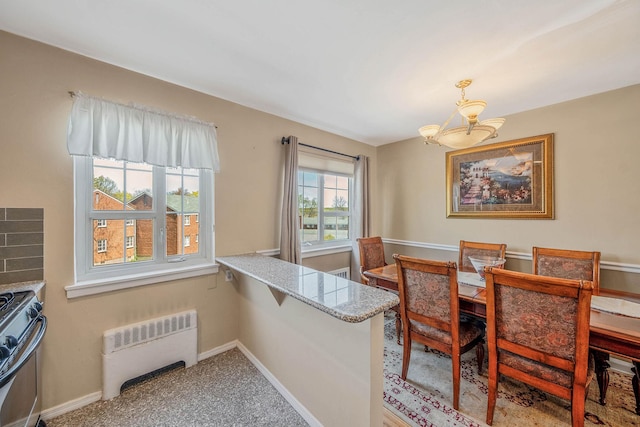 carpeted dining area featuring baseboards, an inviting chandelier, and radiator heating unit