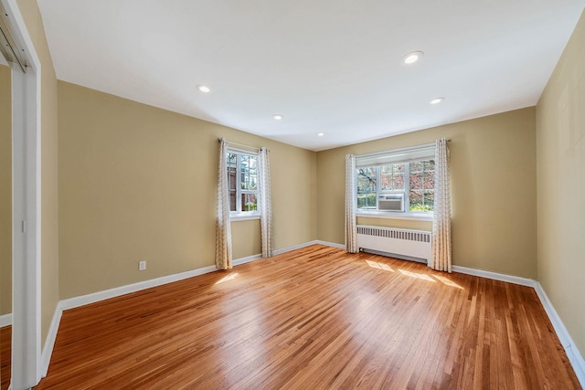 spare room featuring cooling unit, radiator, recessed lighting, baseboards, and light wood-type flooring