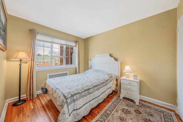 bedroom featuring baseboards, wood finished floors, and radiator