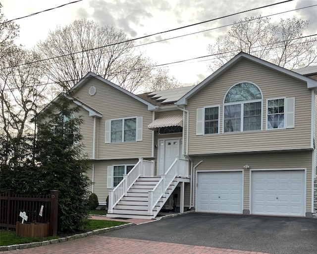 bi-level home with driveway, an attached garage, and fence