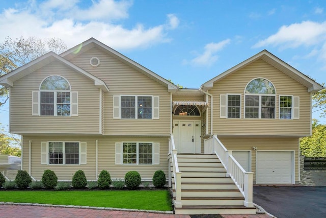 10 12th St, East Hampton, NY 11937 - bi-level home with asphalt driveway, an attached garage, and a front lawn