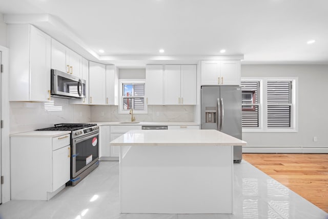 kitchen with stainless steel appliances, a center island, white cabinetry, decorative backsplash, and light countertops