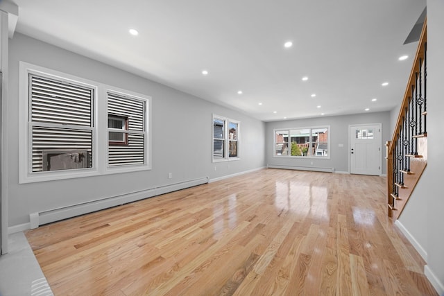 unfurnished living room featuring a baseboard heating unit, light wood-style floors, stairway, and recessed lighting