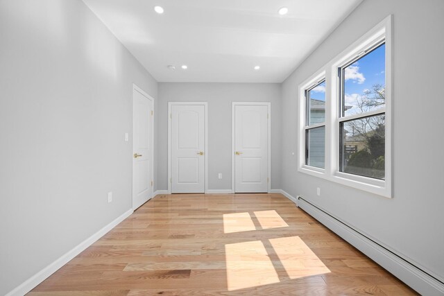 unfurnished bedroom with a baseboard radiator, recessed lighting, baseboards, and light wood-style flooring