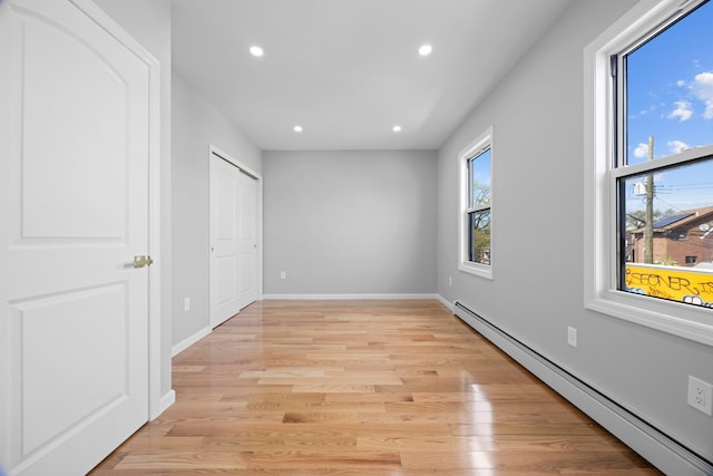 unfurnished bedroom featuring baseboard heating, baseboards, light wood-style flooring, and recessed lighting
