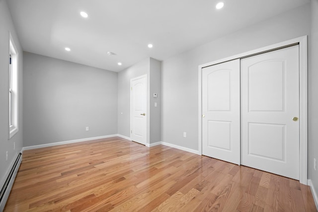 unfurnished bedroom featuring a baseboard radiator, light wood-style floors, baseboards, and recessed lighting
