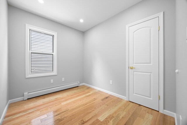 unfurnished room featuring baseboards, wood finished floors, baseboard heating, and recessed lighting
