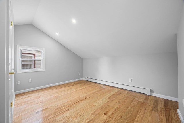 bonus room featuring a baseboard heating unit, lofted ceiling, baseboards, and wood finished floors