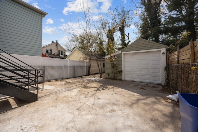 detached garage with concrete driveway and fence