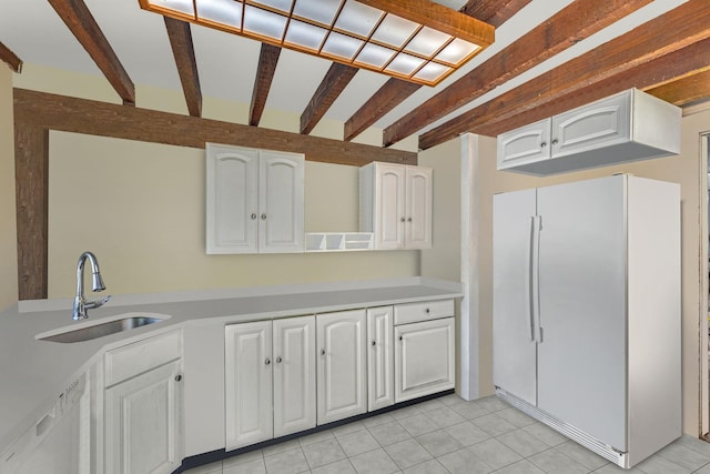 57 River Ave, Cornwall On Hudson, NY 12520 - kitchen with freestanding refrigerator, a sink, white cabinets, beamed ceiling, and light tile patterned flooring